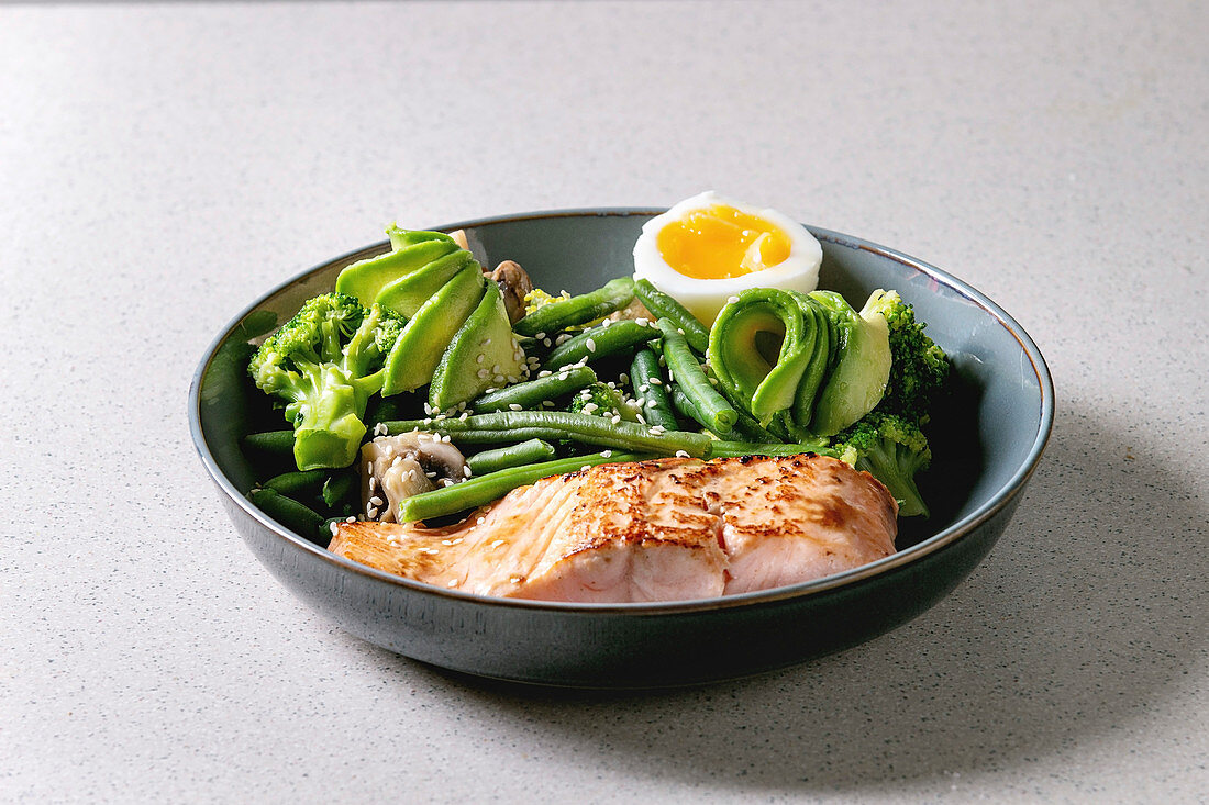 Ketogenic low carb diet dinner grilled salmon, avocado, broccoli, green bean and soft boiled egg