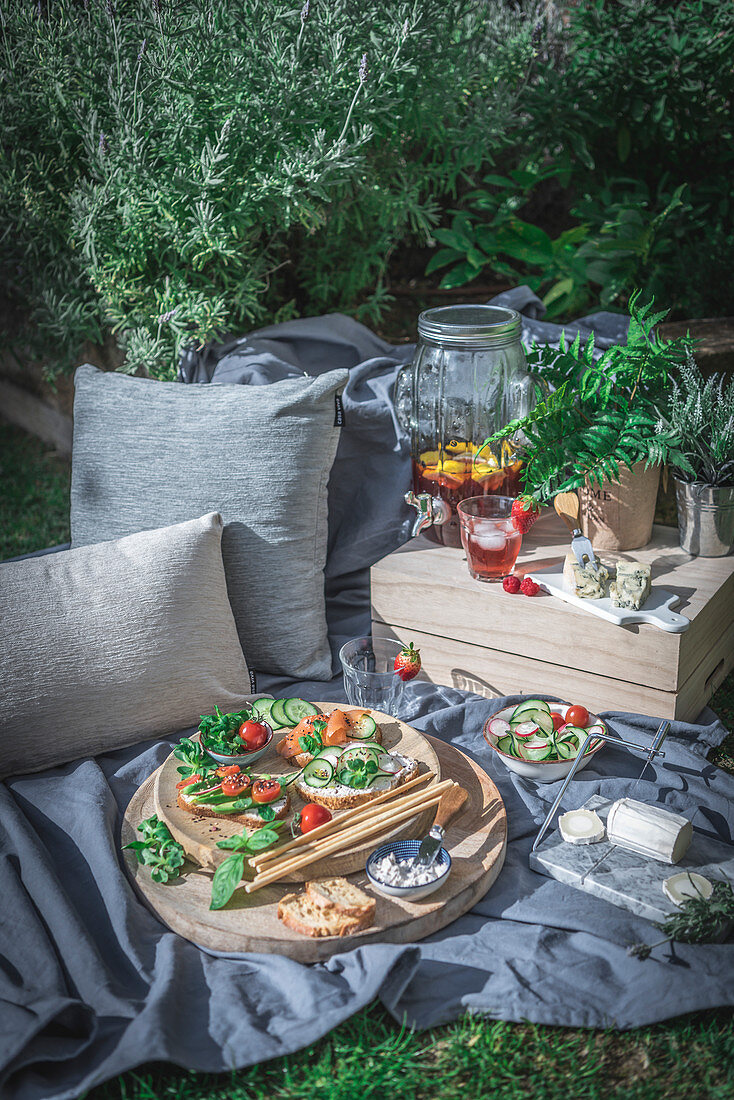 Picknick im sommerlichen Garten mit Bruschetta, Käse und Getränkespender
