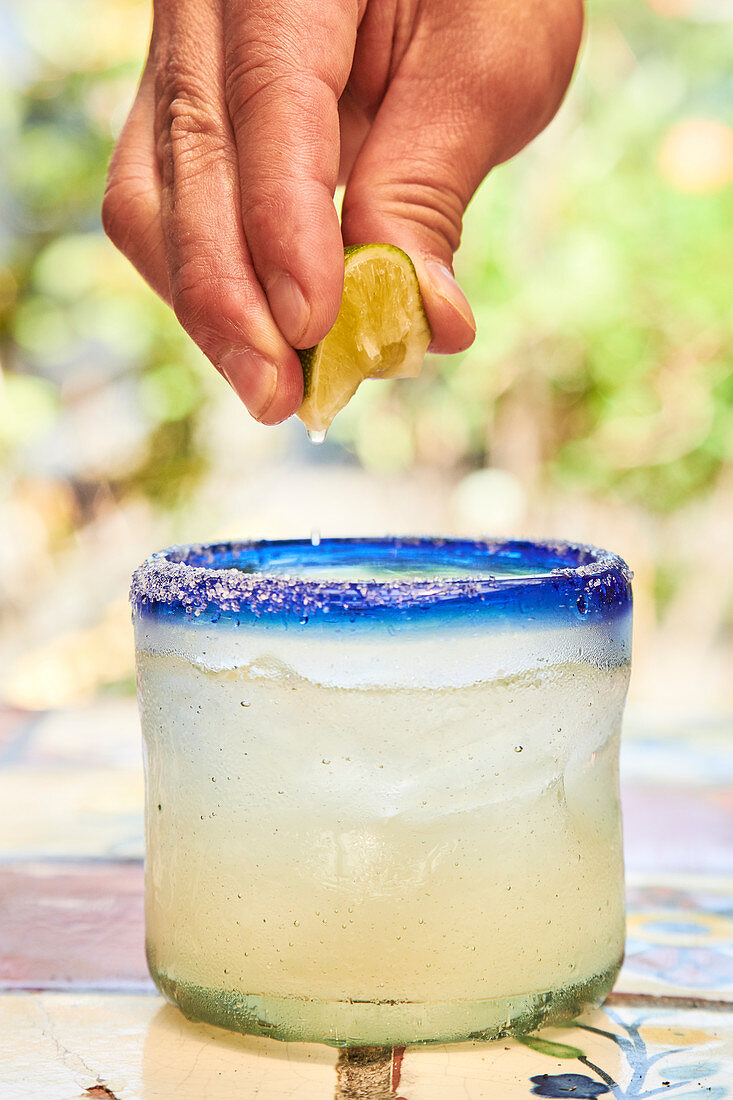 Limettensaft in Cocktail träufeln