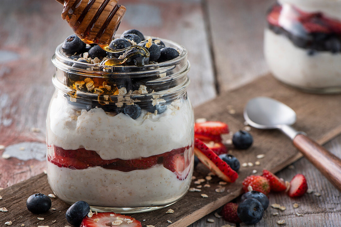 Joghurtmüsli mit Beeren und Honig im Glas