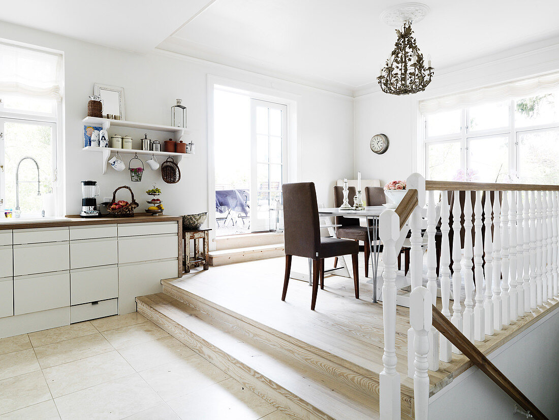 A view from an open-plan kitchen into a dining room two steps higher up