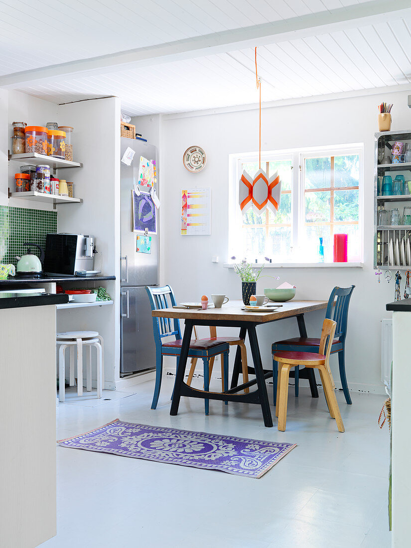 Various chairs at a dining table in kitchen living room with white floor