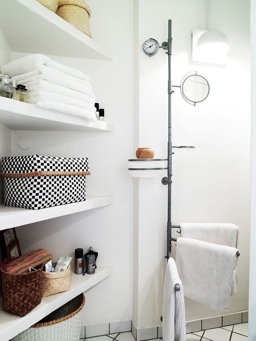 white shelf with towels and care products next to a towel rack