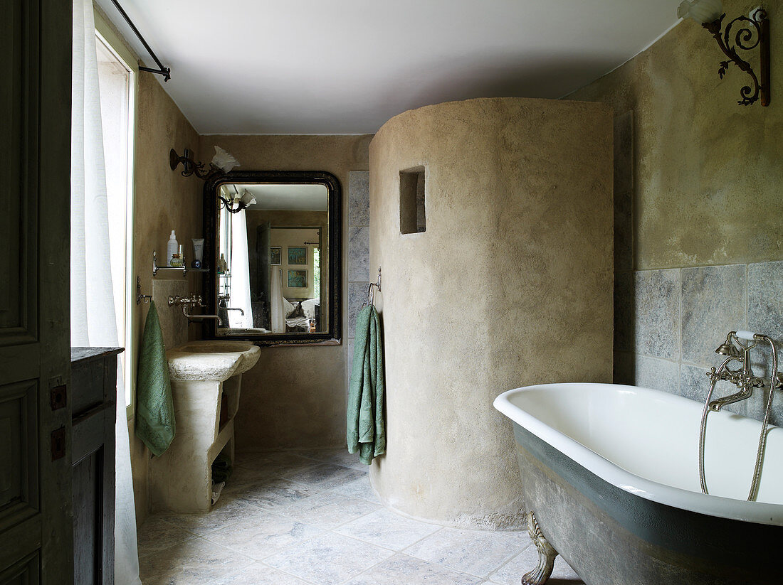 Vintage clawfoot bathtub, concrete shower screen, and vanity in the bathroom