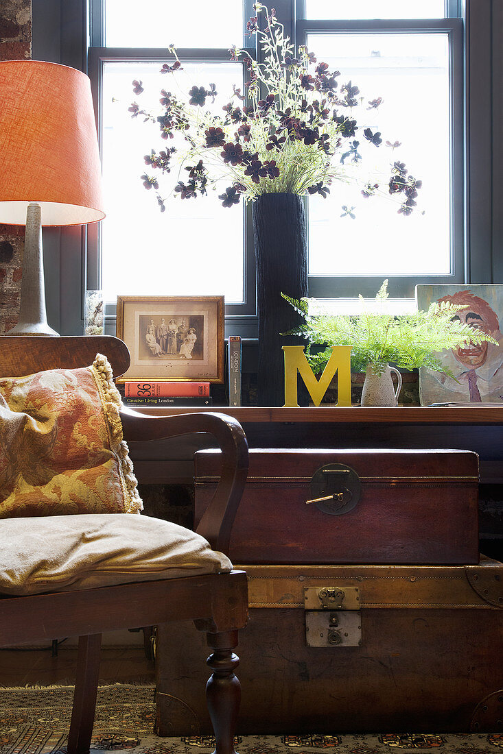 An antique armchair and a vintage suitcase in front of a window