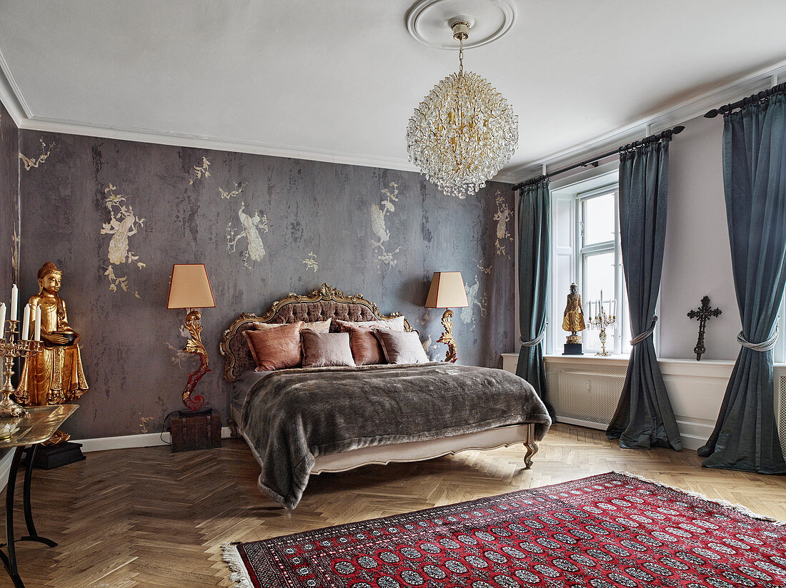 Doppelbett mit antikem Betthaupt, flankiert von Stehleuchten und goldfarbene Statue im Schlafzimmer