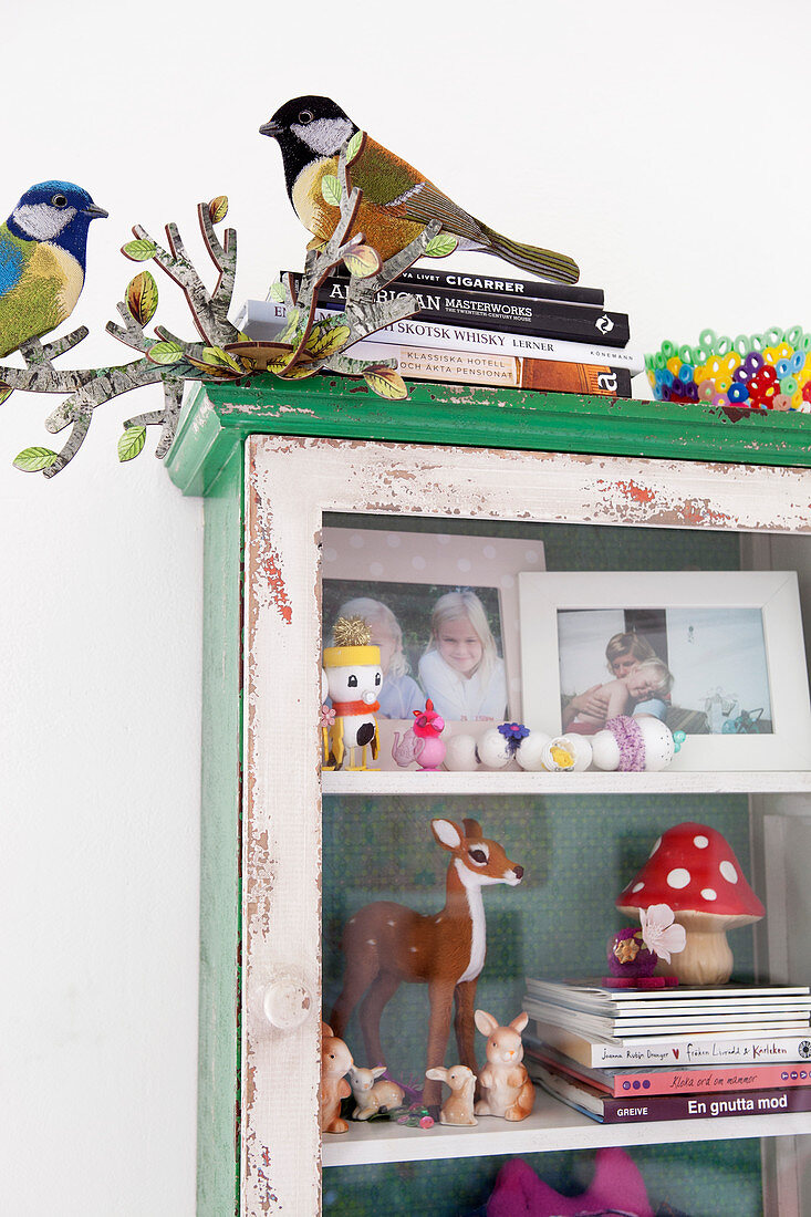 An old glass cabinet filled with family photos, animal figures and books