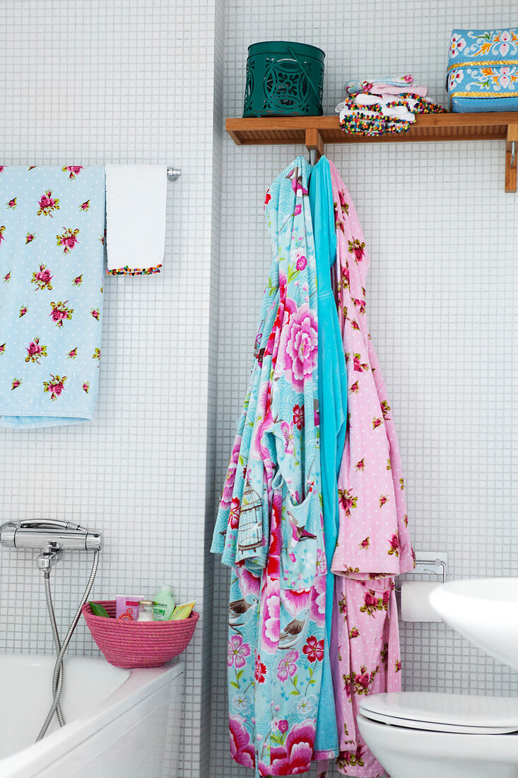 Colourful bathrobes in a bathroom with white mosaic tiles