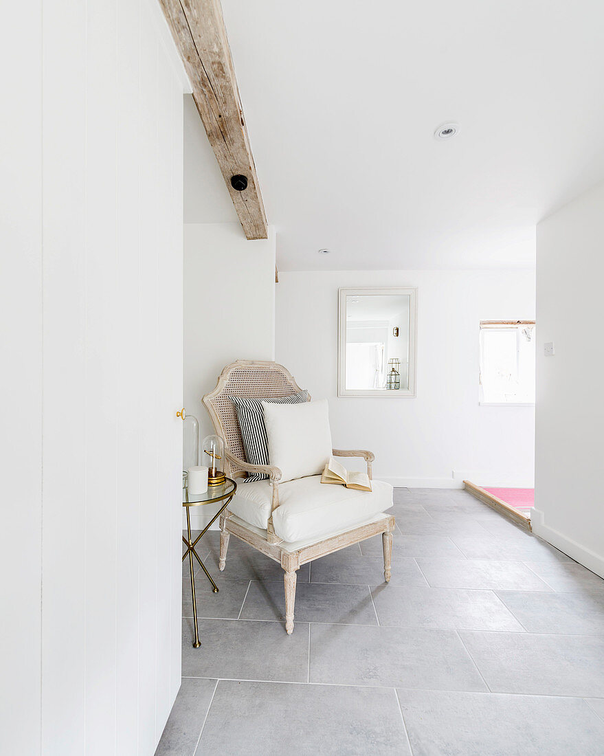 Antique armchair and round side table in seating area of converted barn