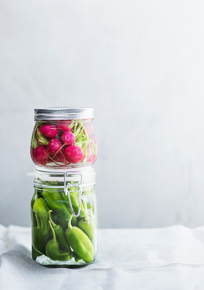 Pickled chili peppers and radishes in glass jars