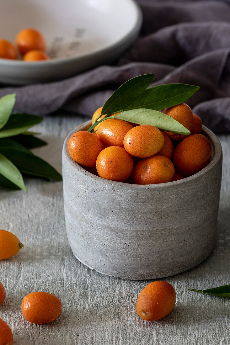 Fresh kumquats in a grey ceramic bowl
