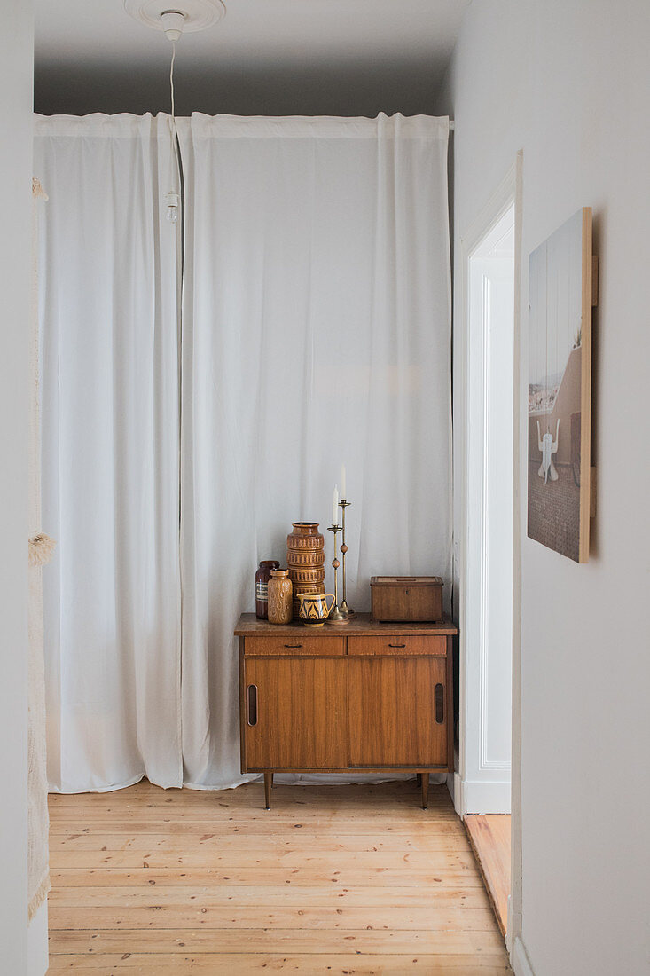 Retro vases on old cabinet against curtains in hallway