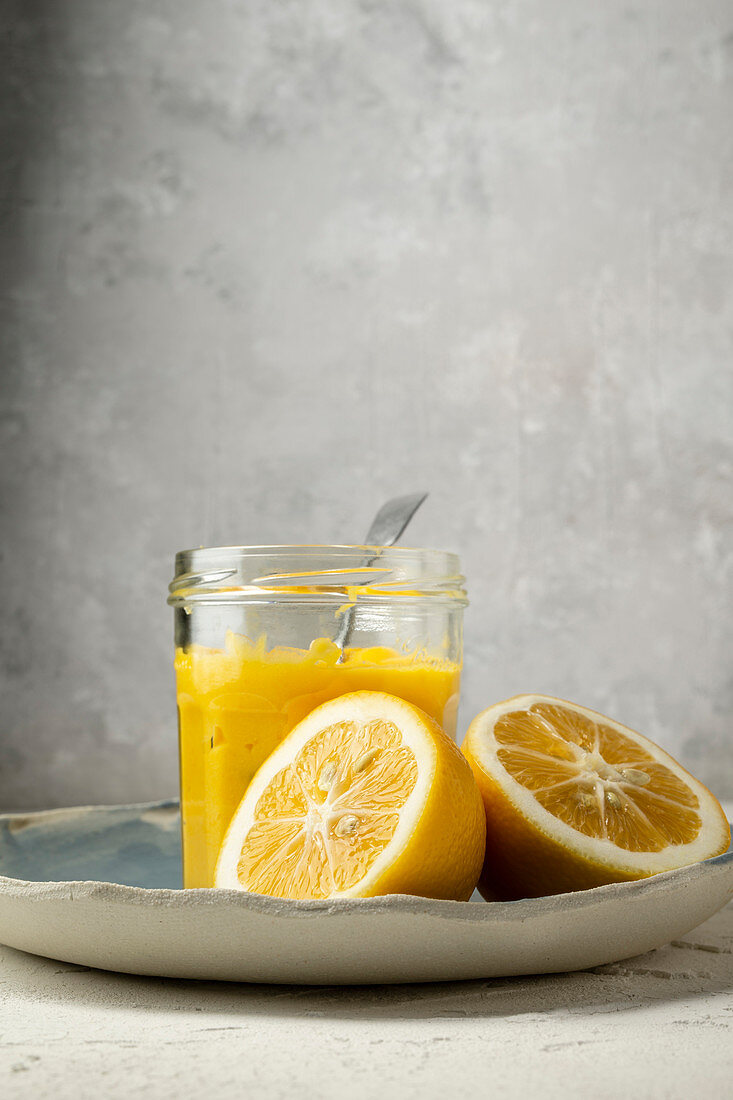 Lemon curd in a screw-top jar next to lemon halves