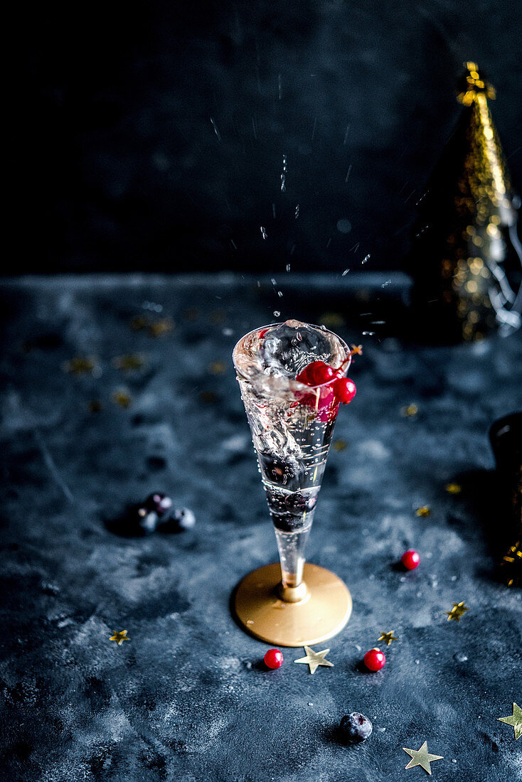 A glass of sparkling champagne with blueberries and redcurrants