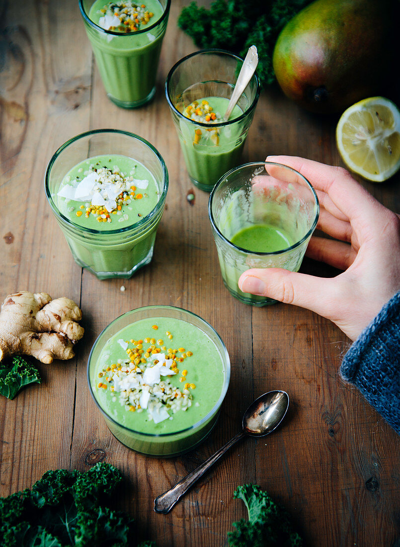 Hand hält Glas mit grünem Smoothie