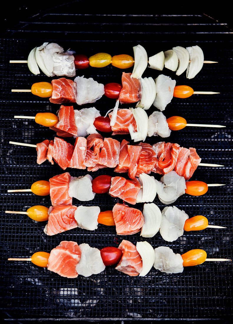 Raw fish skewers with cherry tomatoes on a barbecue