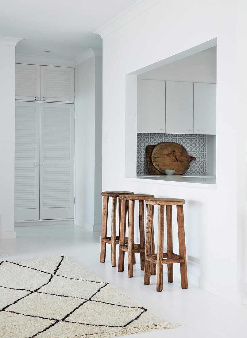 Wooden stool in front of serving hatch between kitchen and dining room