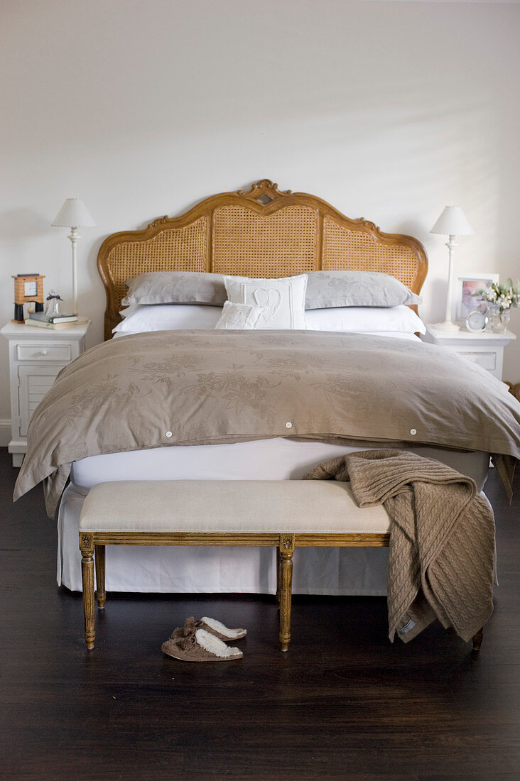 Bedroom bench at foot of antique bed in brown-and-white bedroom