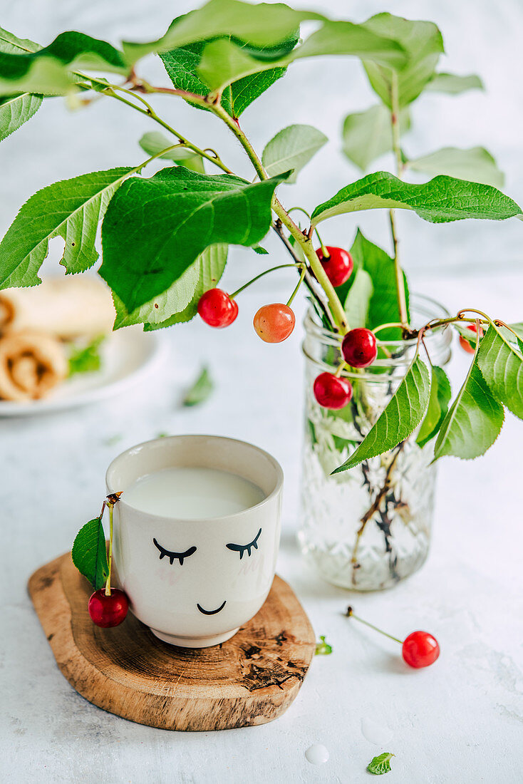 Milk in a smiling mug, fresh cherry