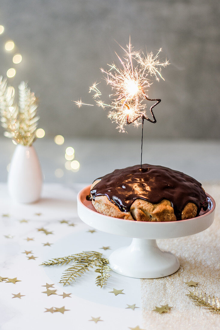 New Year's cake with chocolate glaze, asterisk cold sparkles, golden additions