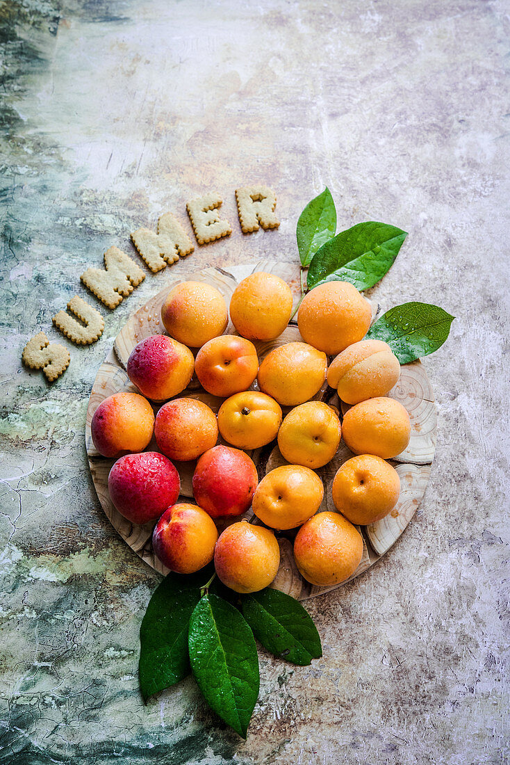 Fresh apricots with a green leaf on a wooden board, summer cookie inscription