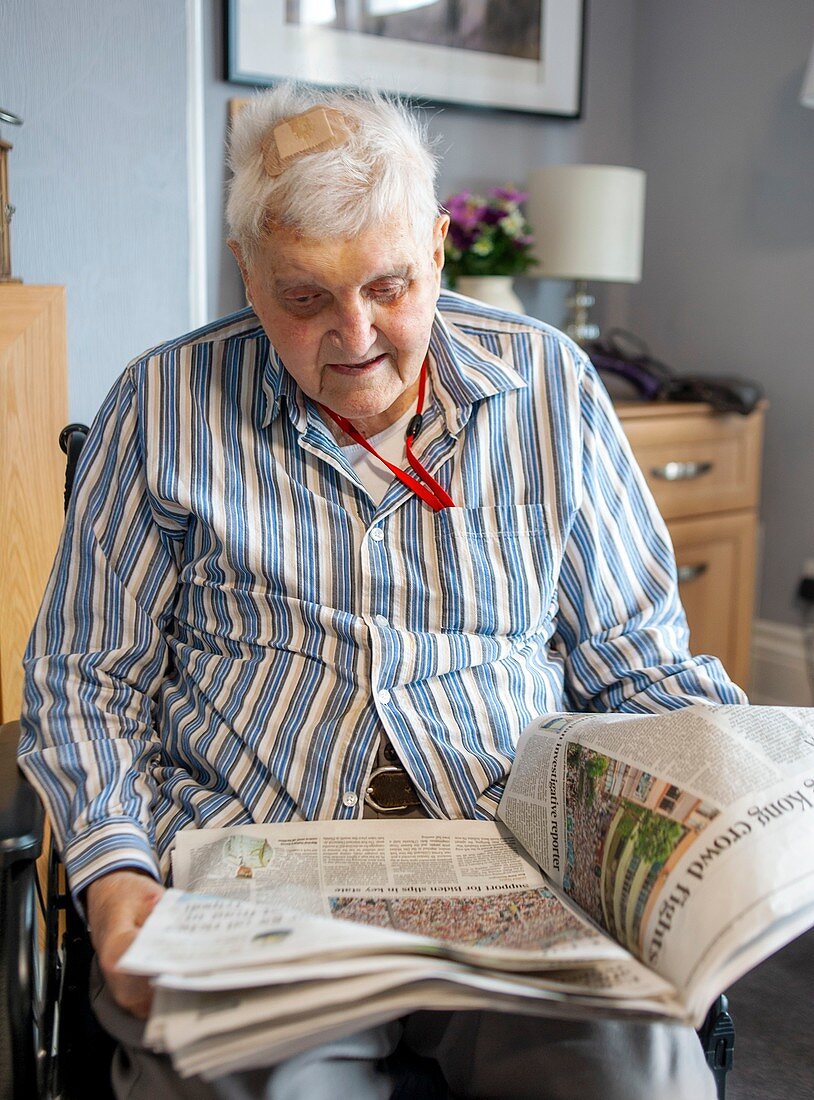Care home resident reading a newspaper