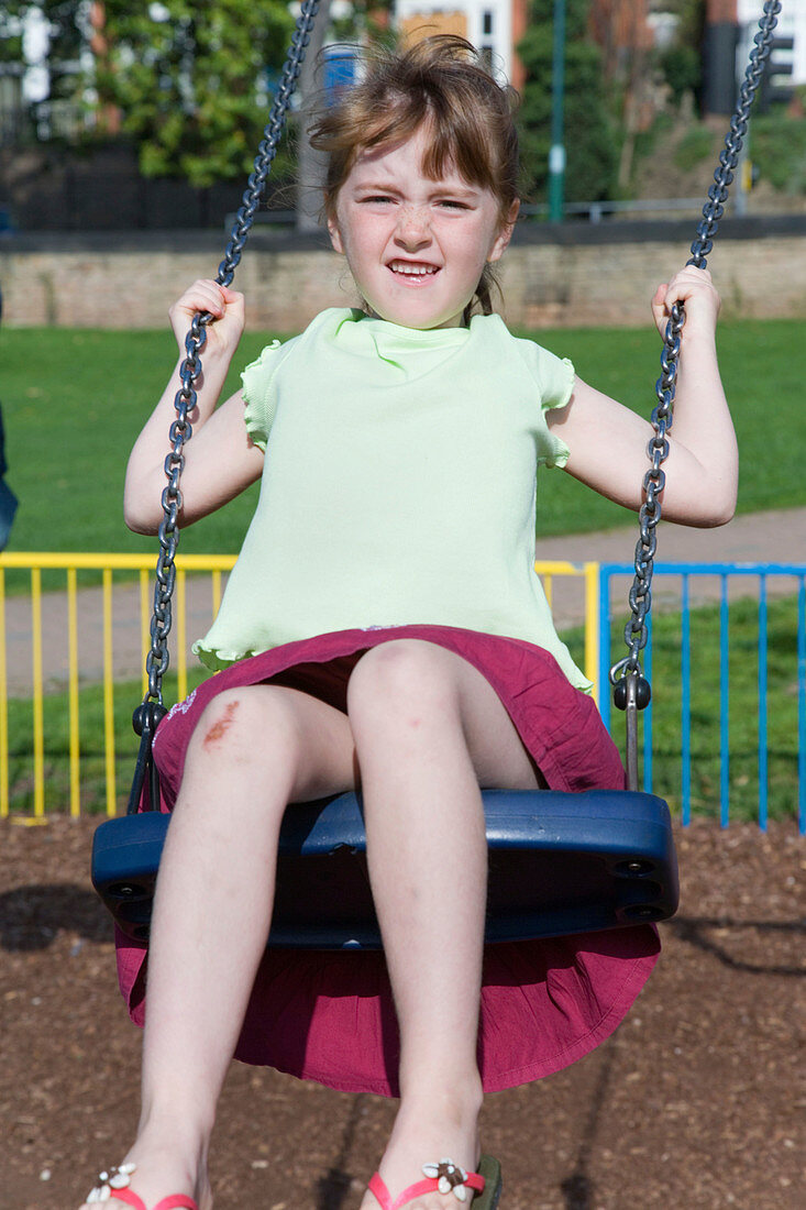 Young girl swinging on a playground swing