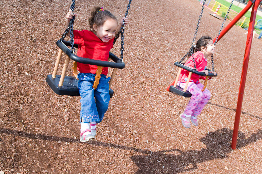 Young girls swinging on playground swings