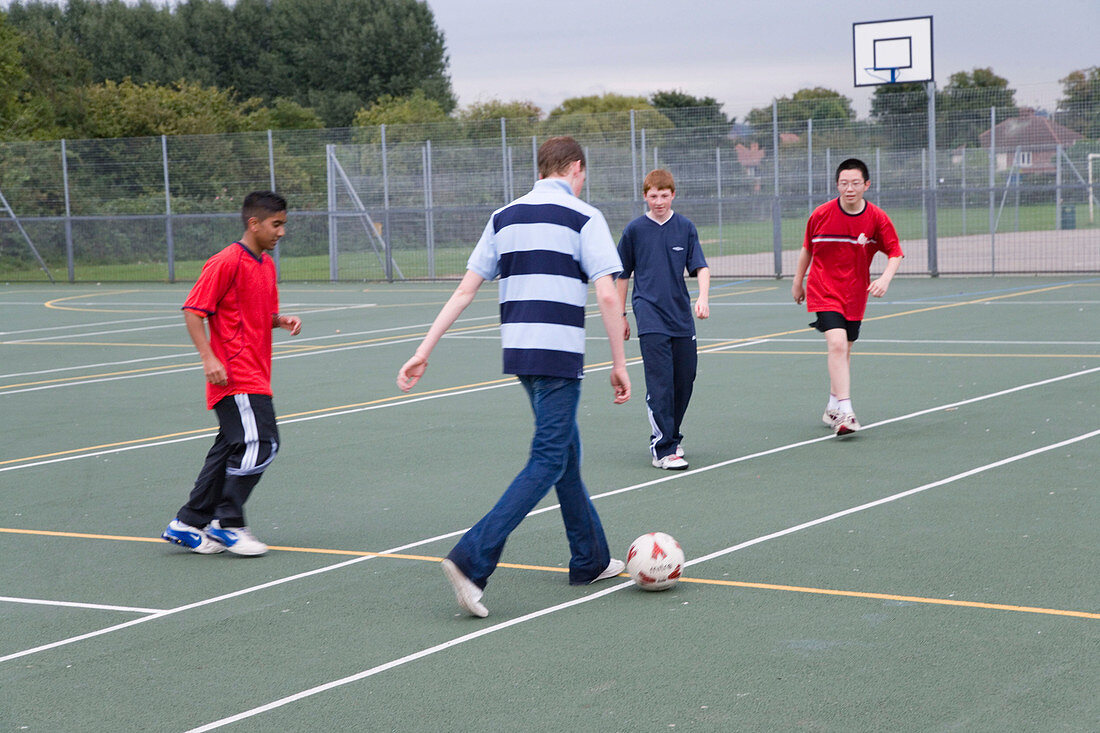Group of teenage boys having a kick about with a football