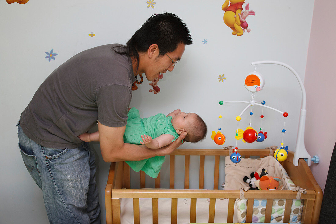 Chinese father putting his baby daughter to bed