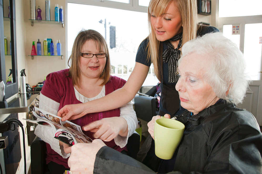 Carer with old woman at hairdresser's choosing hair style