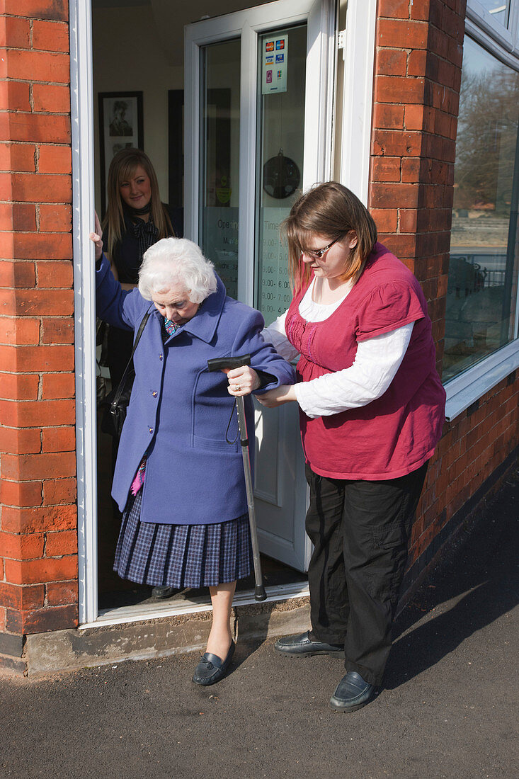 Carer helping old woman down step