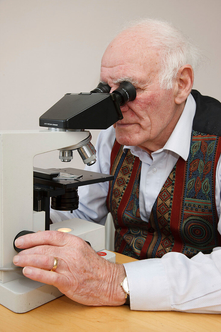 Elderly man looking through microscope