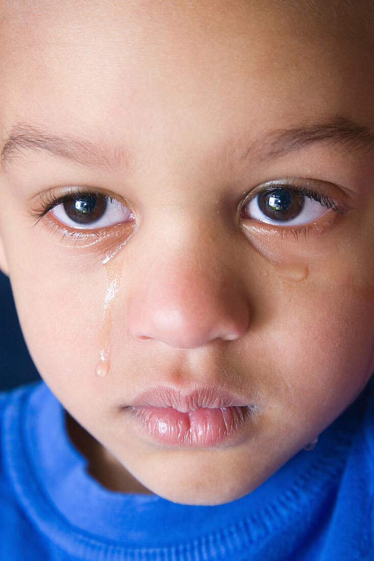 Upset young boy with tears streaming down his face