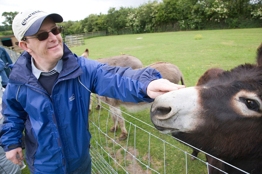Man with learning disabilities feeding a donkey