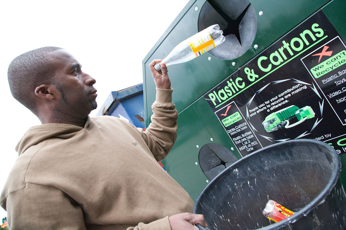Man putting plastic bottle into recycling bank