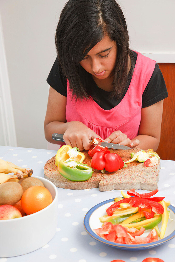 Teenage girl cutting peppers