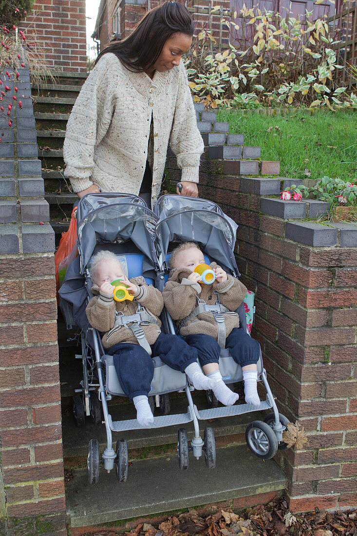 Mother going up steps with twins in buggy