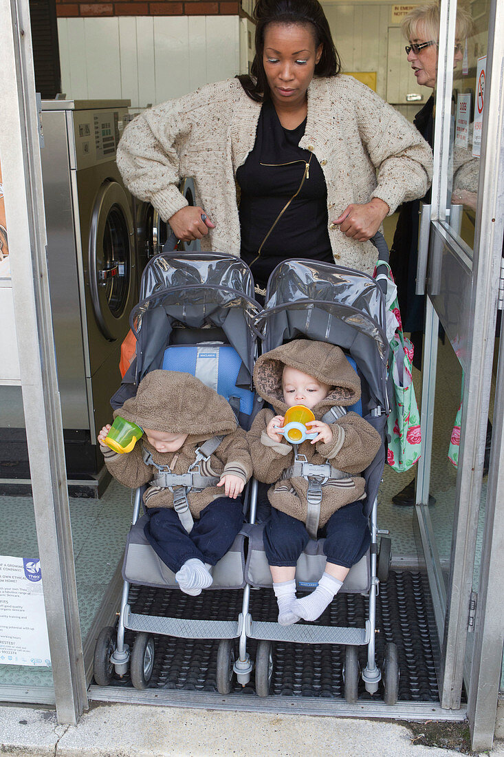 Mother with twins in buggy at launderette