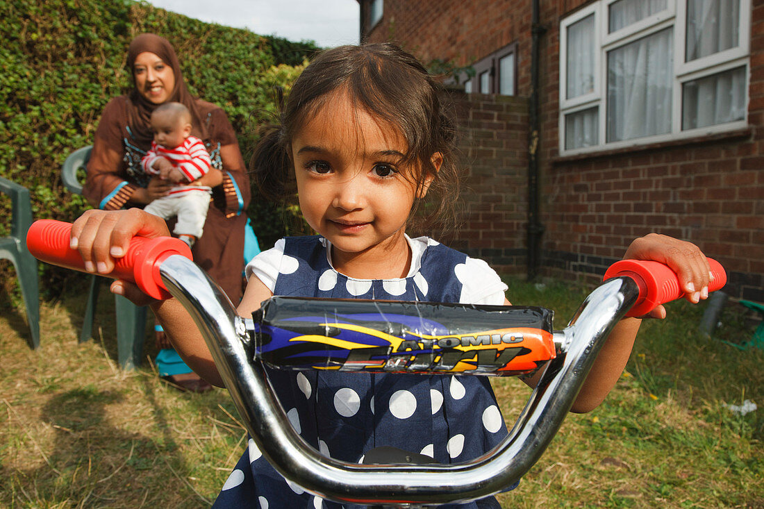 Girl on trike with mother behind