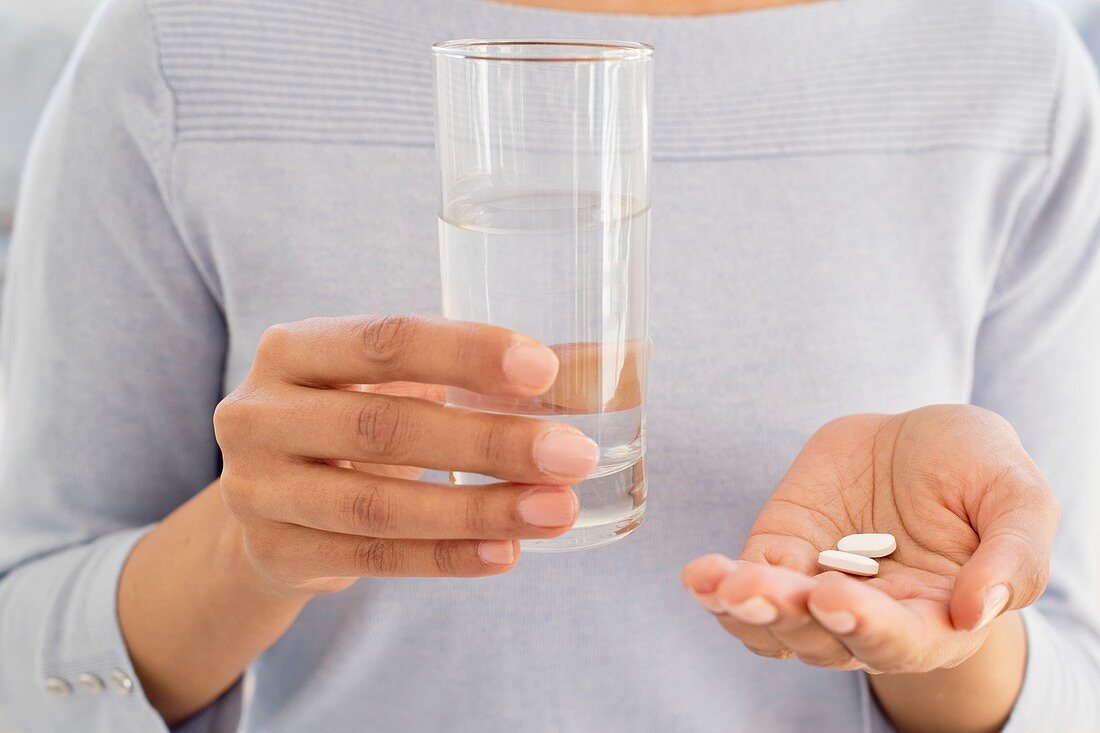 Woman holding tablets and water