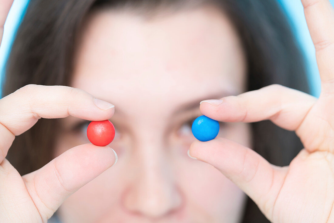 Woman holding pills in front of eyes