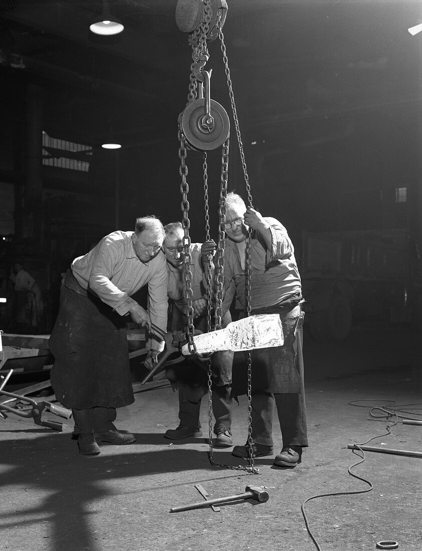 Three workers handle a red hot billet, 1963