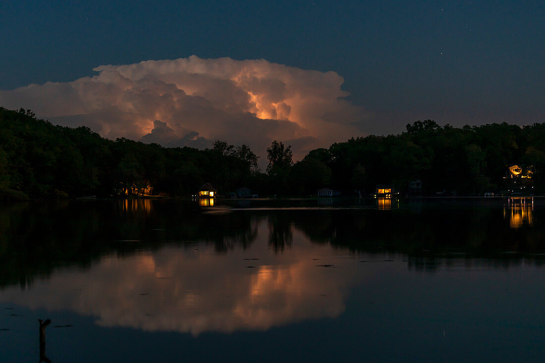 Lightning in clouds reflected in lake