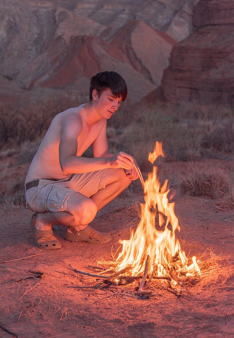 Young man lighting a campfire