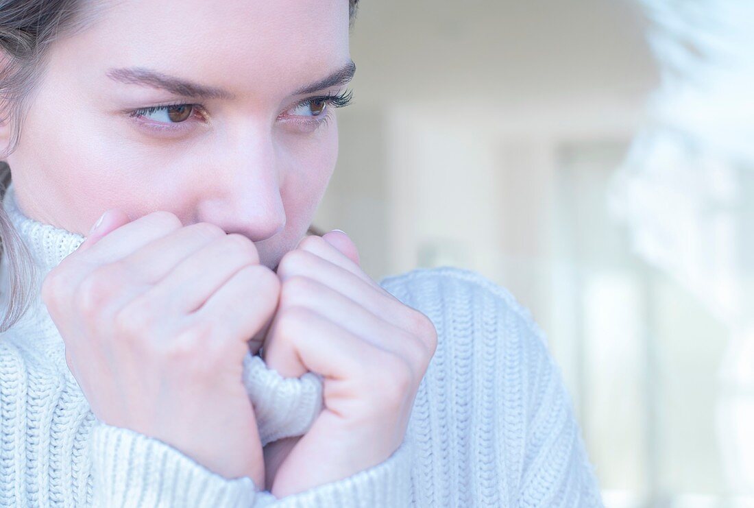 Young woman clasping neck of sweater