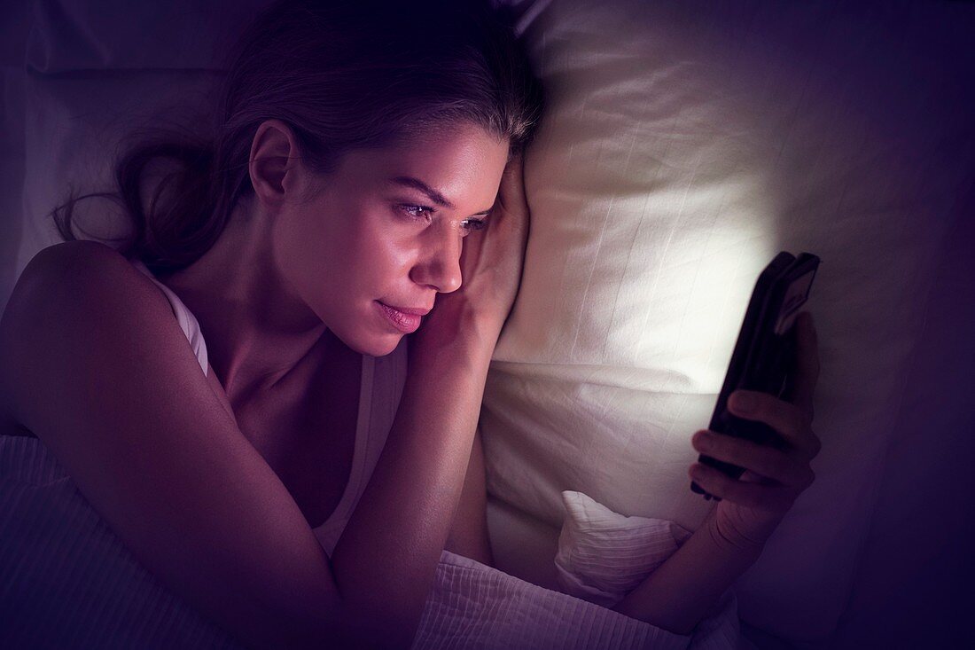 Young woman looking at smartphone in bed