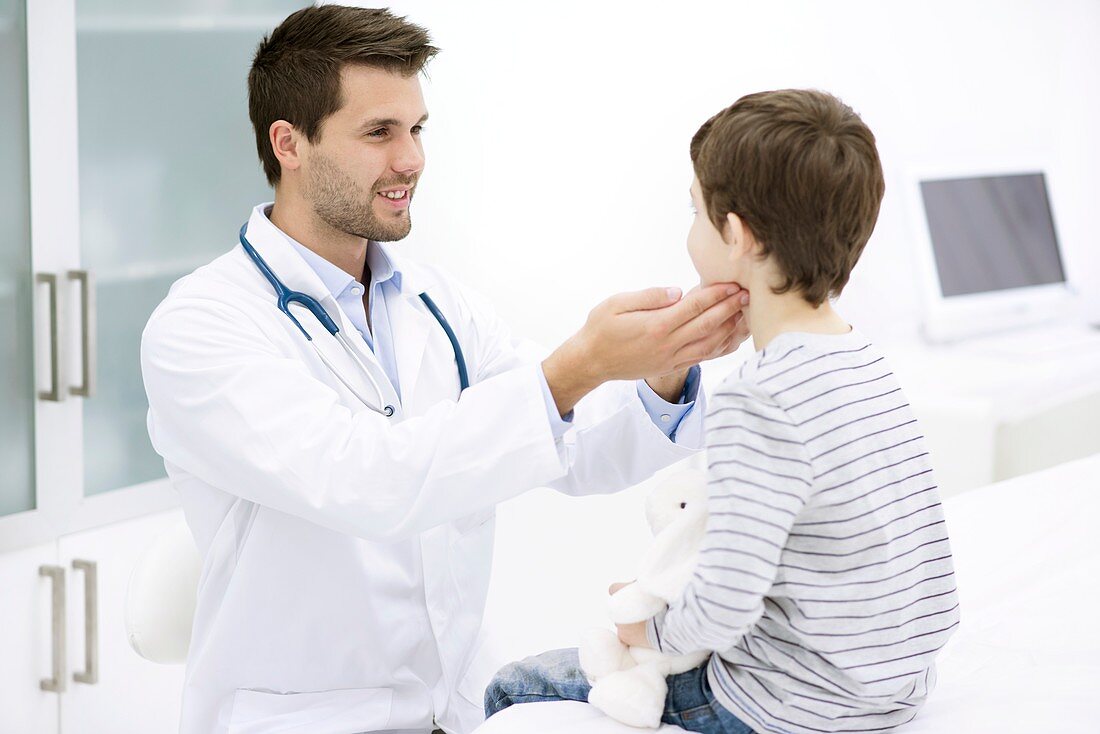 Doctor examining boy's neck