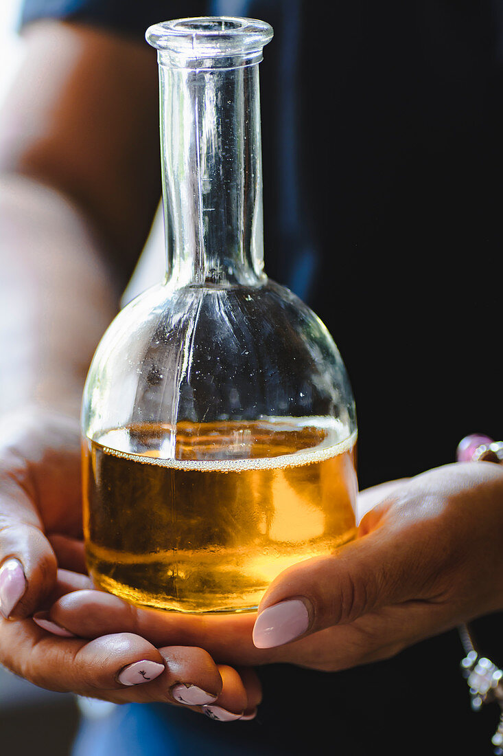 Women holding linseed oil in glass bottle