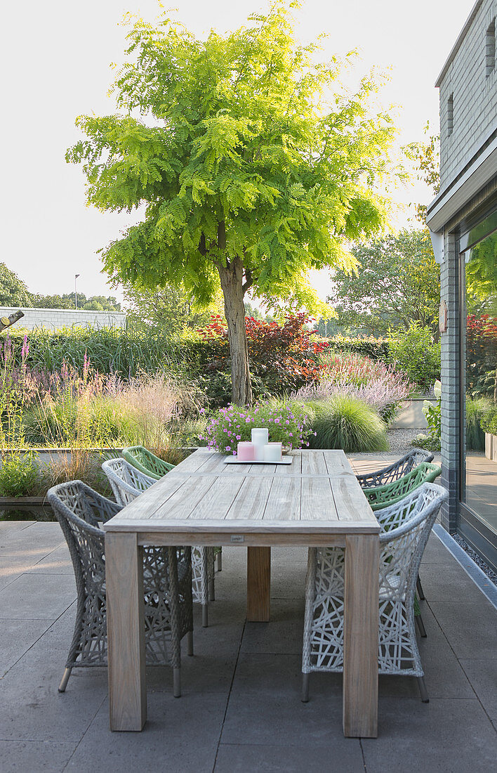 Holztisch und Designerstühle auf Terrasse mit Betonfliesen